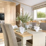 ABI Ambleside dining table laid for four with upholstered chairs, next to the kitchen window and integrated oven