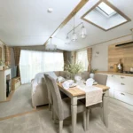 ABI Ambleside kitchen and dining area with a dining table for four, gas hob and cooker hood, looking to the lounge