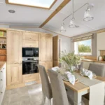 ABI Ambleside kitchen with tall cabinets, integrated oven, wicker storage baskets and a gas hob beside the dining table