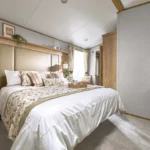 ABI Ambleside main bedroom with a king size bed, tall padded headboard, bedside cabinets and wall lights