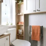 ABI Ambleside shower room with a countertop basin, toilet, open shelving, wall cupboards and a chrome towel rail