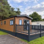 Side view of new Love Holiday Homes lodge with decking and private parking space